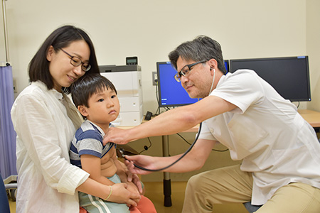 医師が男の子の胸に聴診器をあてて診療している様子の写真