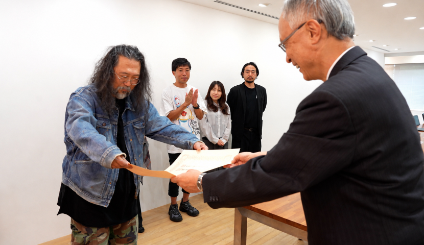 五十嵐理事長から村上隆さまへの褒章伝達の様子